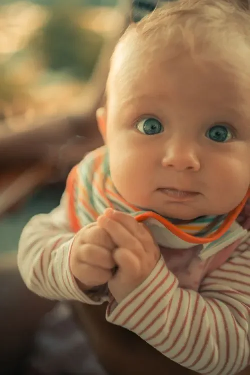 A baby with wide blue eyes looking directly ahead