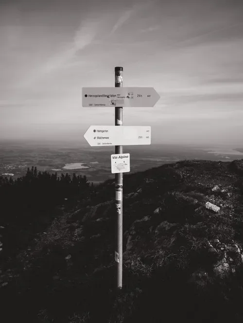 A mountain path with a signpost at sunrise