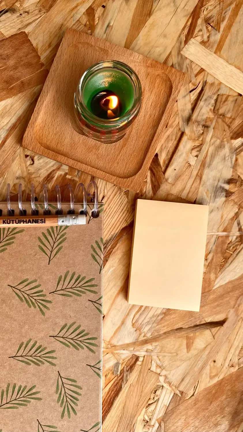 Lit candle and a notebook on a wooden desk