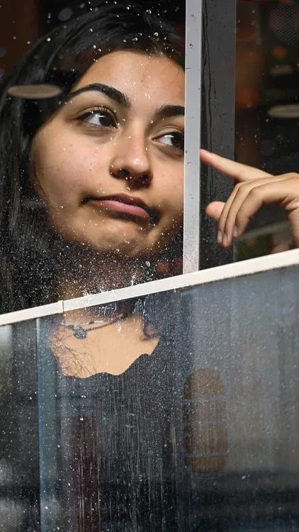 A pensive woman looking out through a rainy window