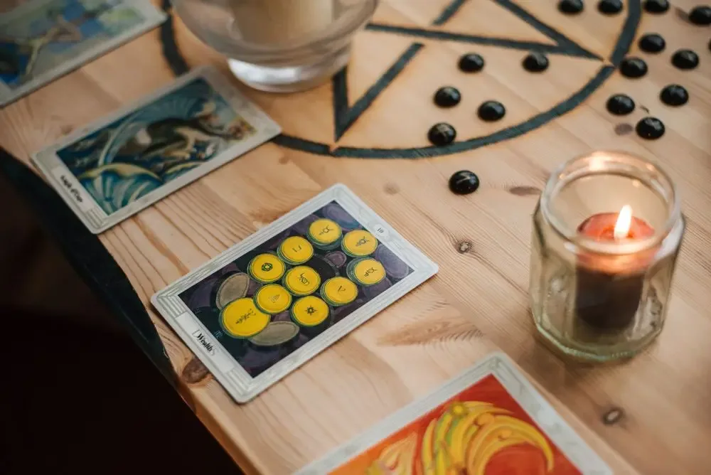 Burning candle next to tarot cards on a table