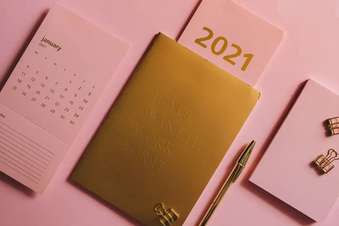 Planner and calendar on a pink background, a note for the year ahead