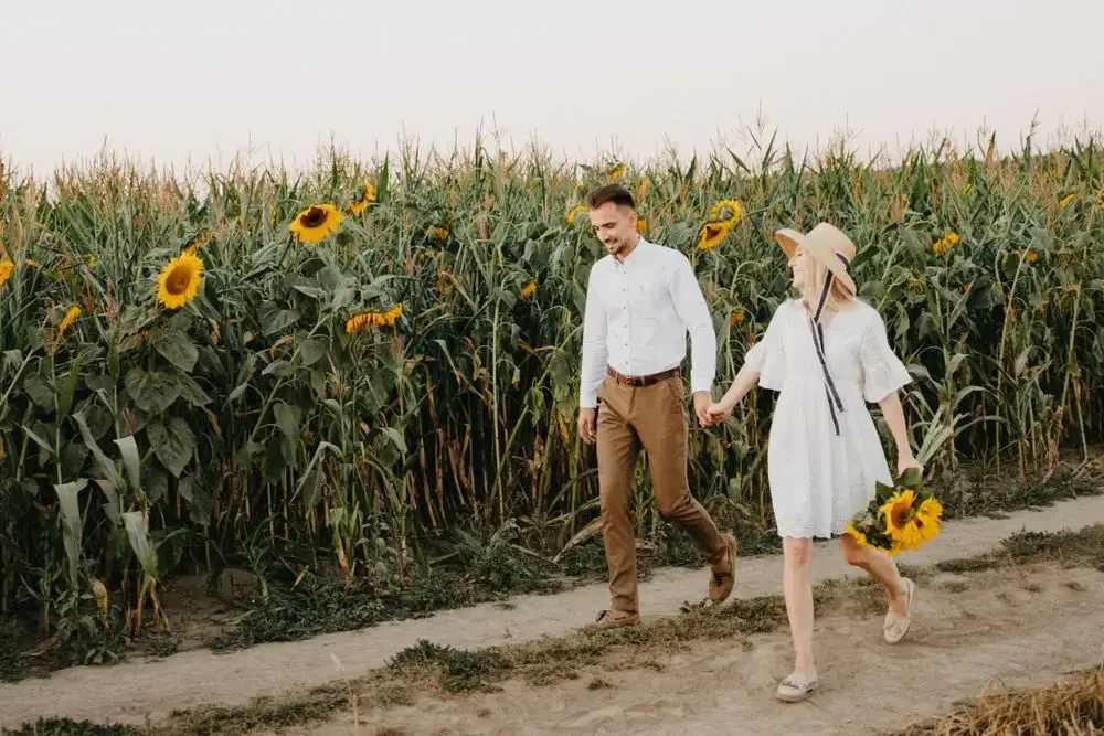 A couple walking hand in hand through a sunflower field