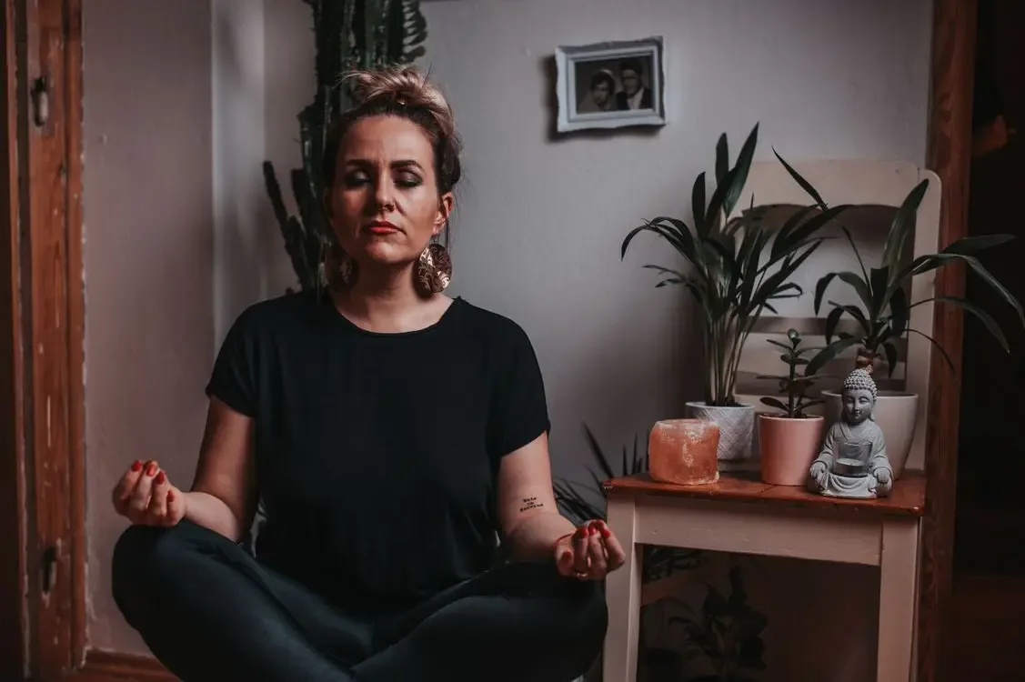Calm woman meditating with closed eyes at home