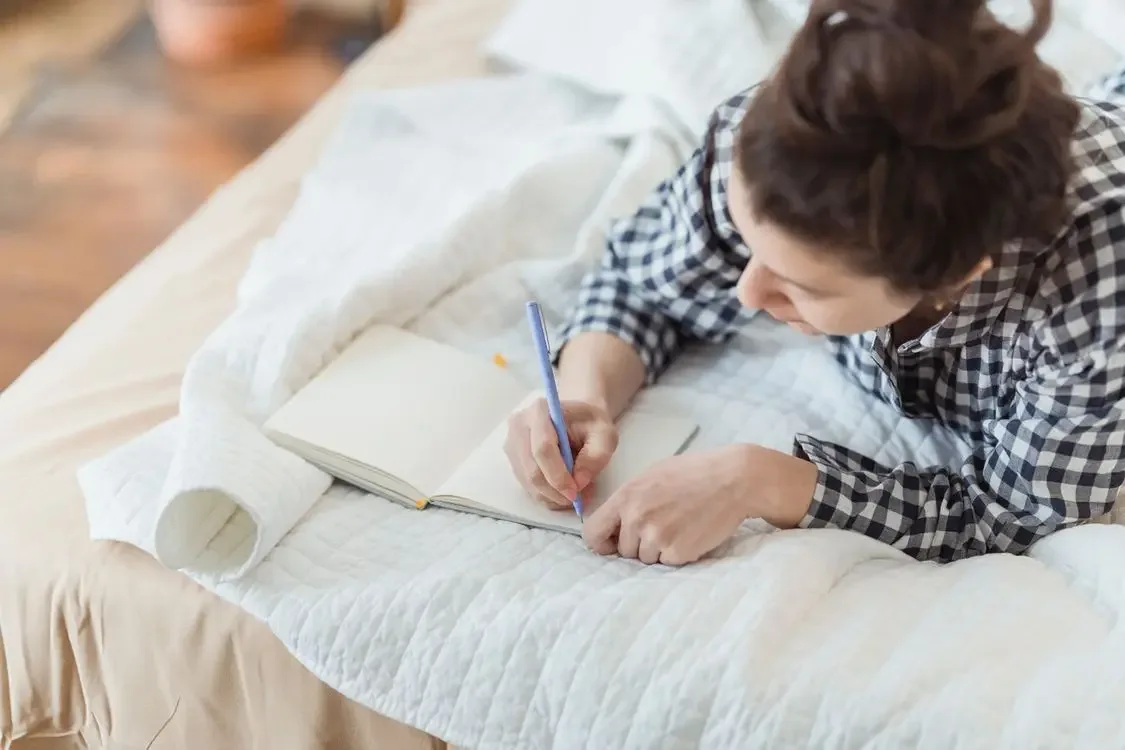 Woman journaling in bed, a quiet birthday review