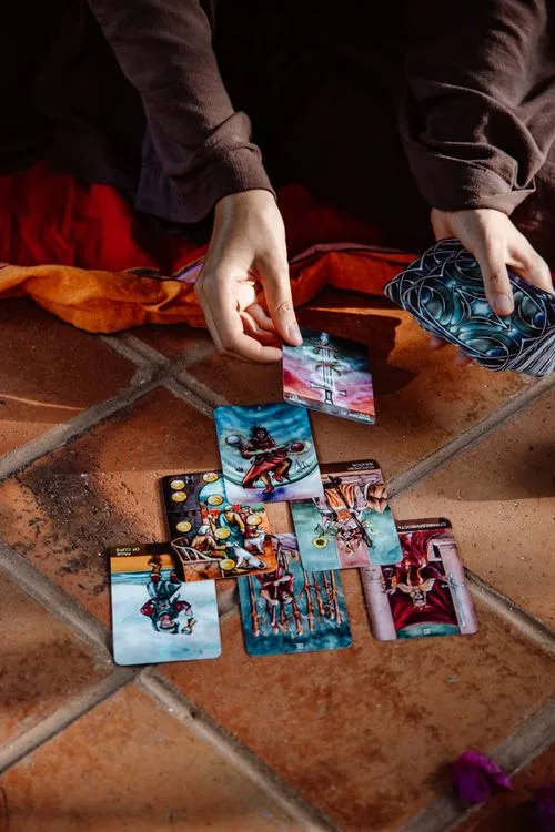 Hands arranging a tarot spread on a tiled floor