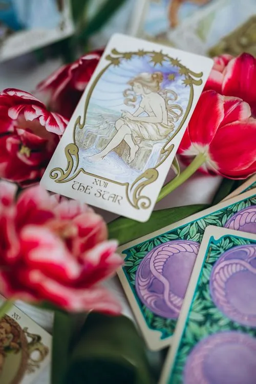 A Star tarot card displayed among flowers and other cards