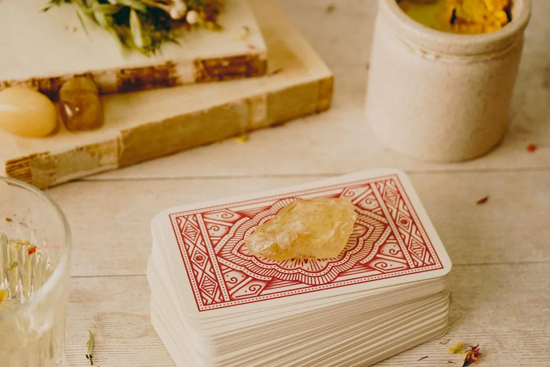 A tarot deck beside a crystal and other reading objects
