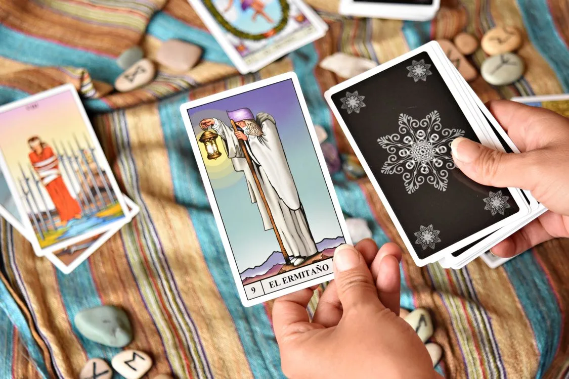 A tarot reader holding The Hermit beside a spread of cards