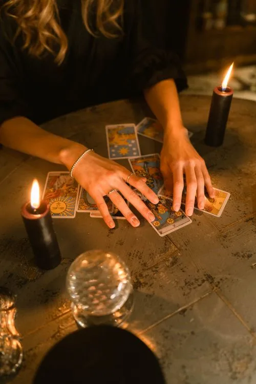 A reader arranging tarot cards beside candles