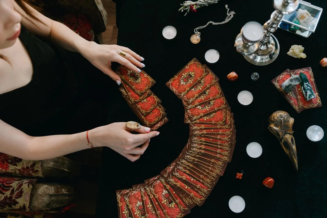 Hands choosing from a fan of tarot cards on a dark table